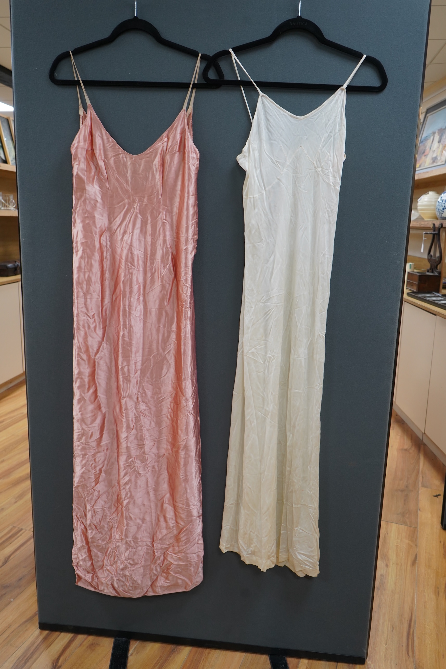 Two late 19th early 20th century long baby night gowns and two shorter baby gowns, together with a pink satin ladies full length slip and a similar cream silk stockinette slip, the bodices worked on baby dresses are embr